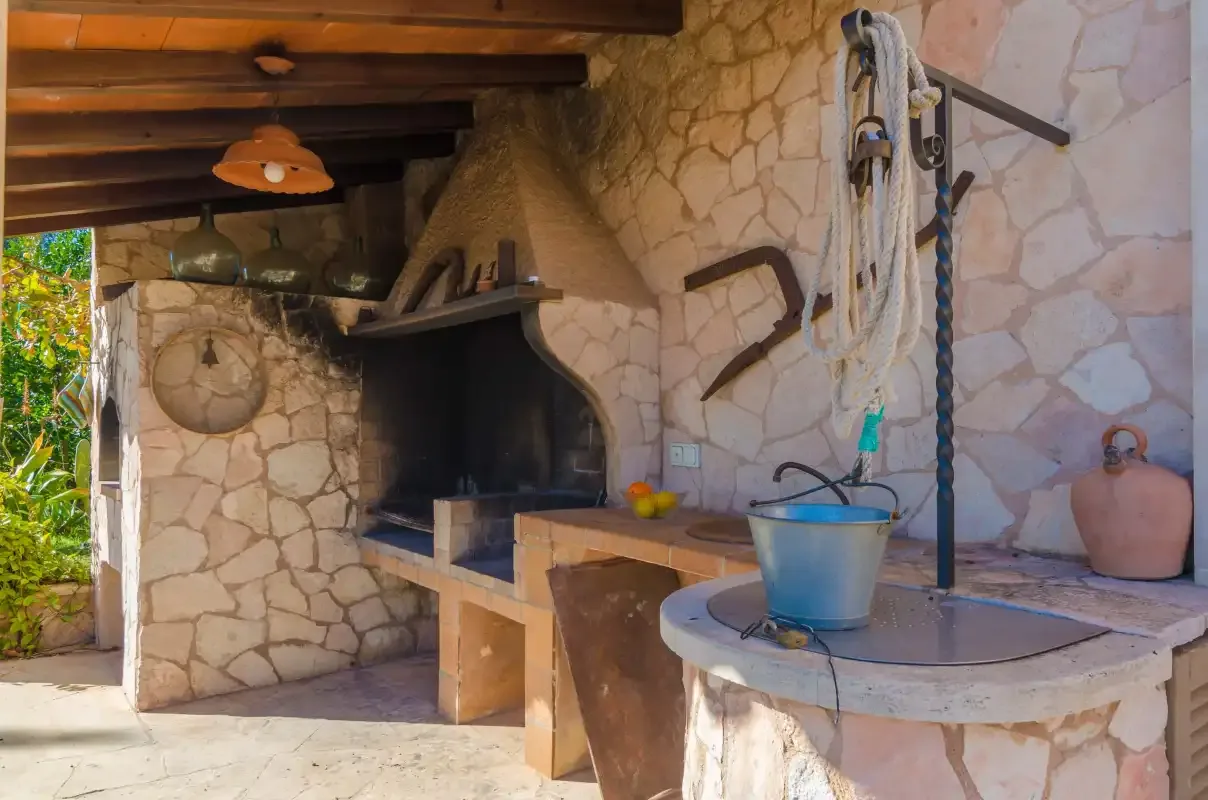 An outdoor stone cooking area with a built-in grill and countertop.