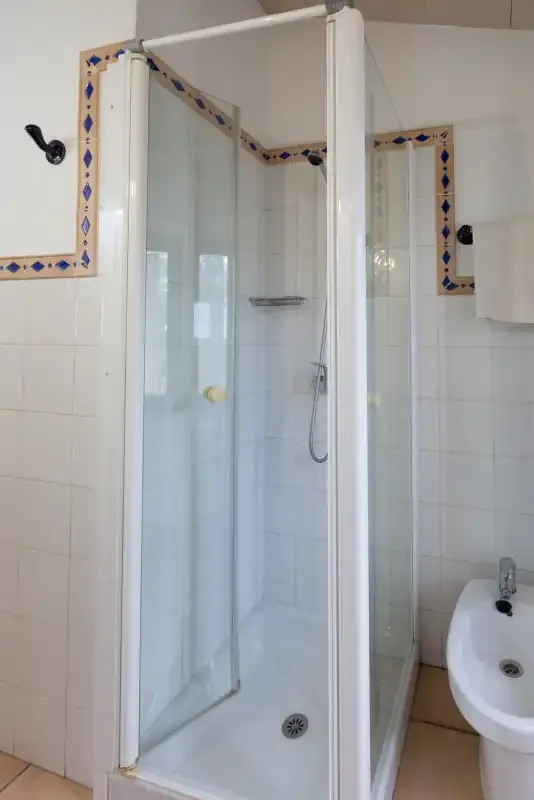 A tiled bathroom with a glass shower and a wall-mounted sink.