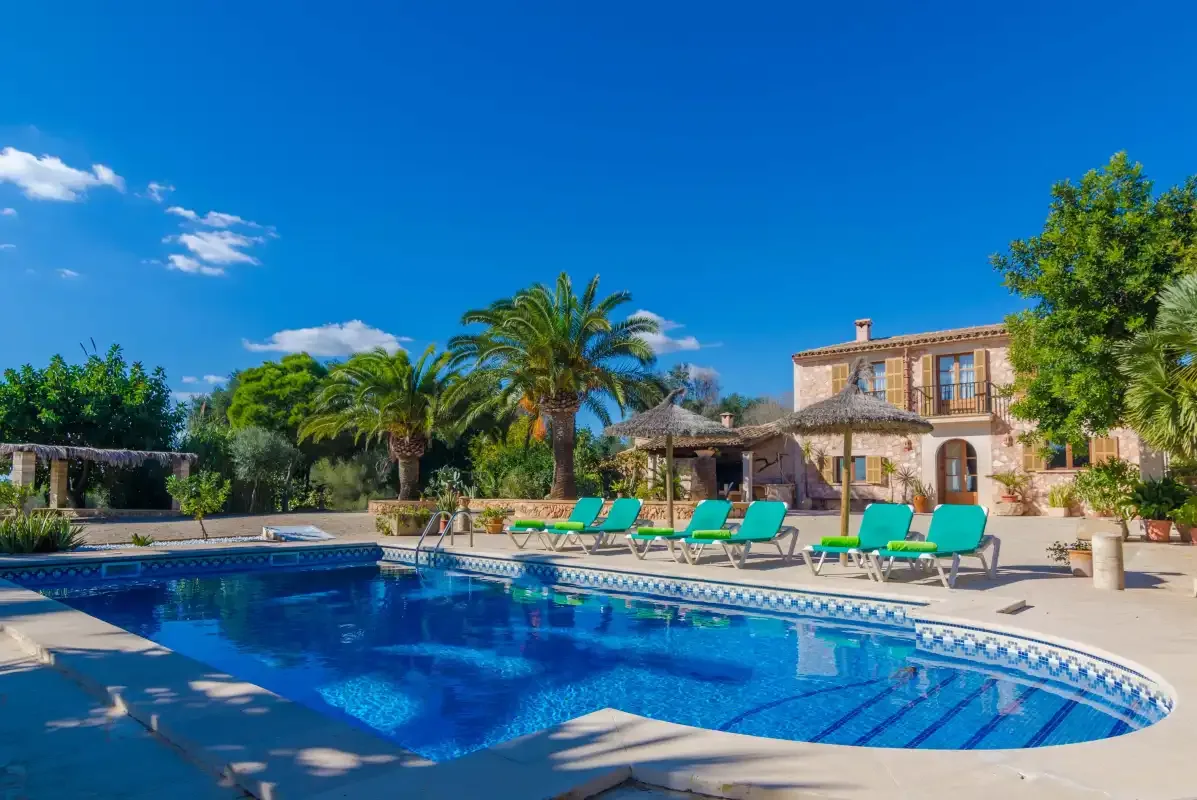 Outdoor swimming pool beside a paved patio and a two-story building.