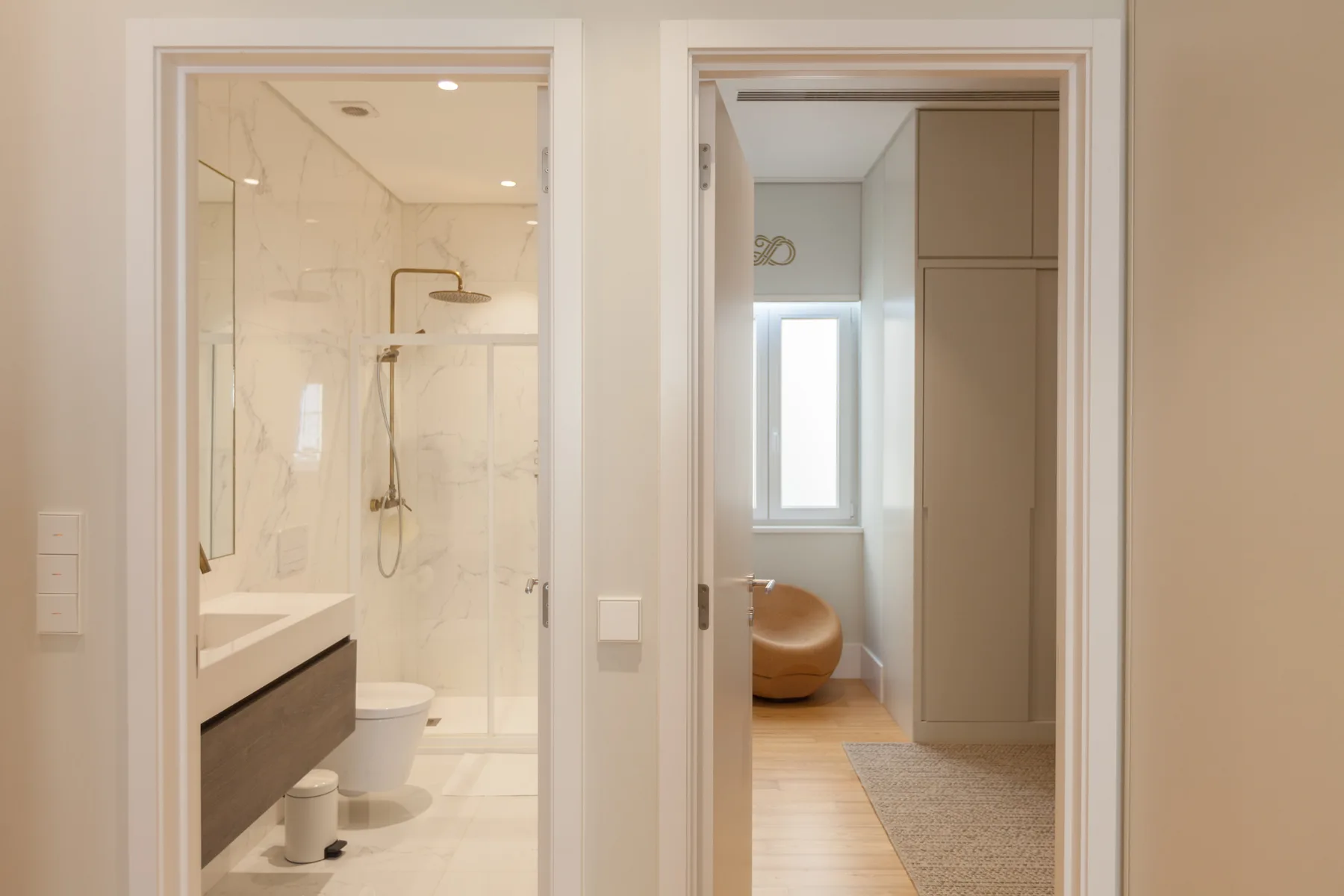 A bathroom with a shower and a view into an adjoining room.