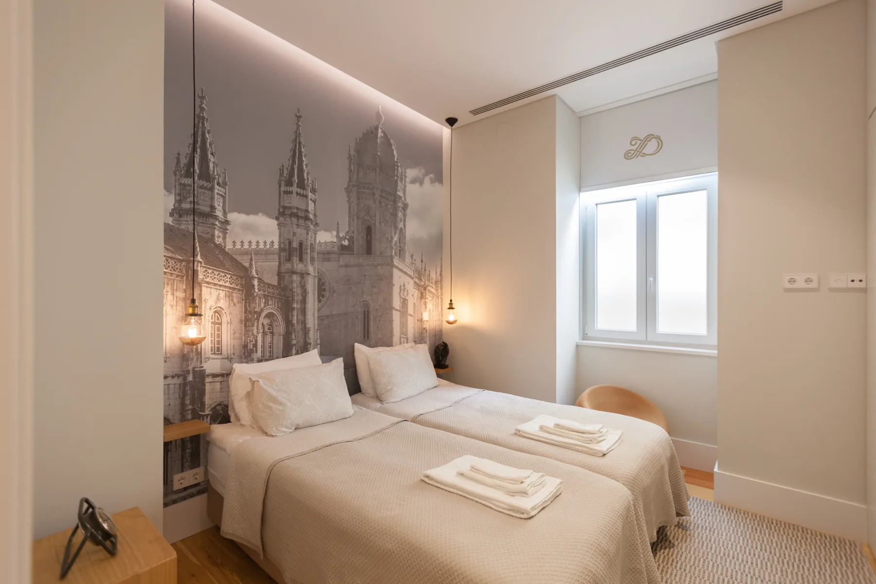 A bedroom with a neatly made bed and a large architectural mural.