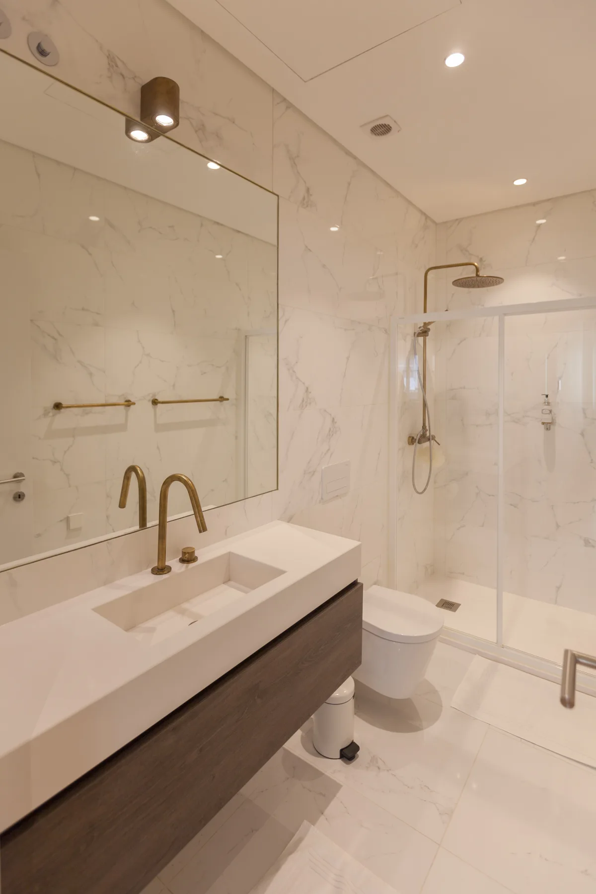 A bathroom with a vanity, mirror, toilet, and shower.