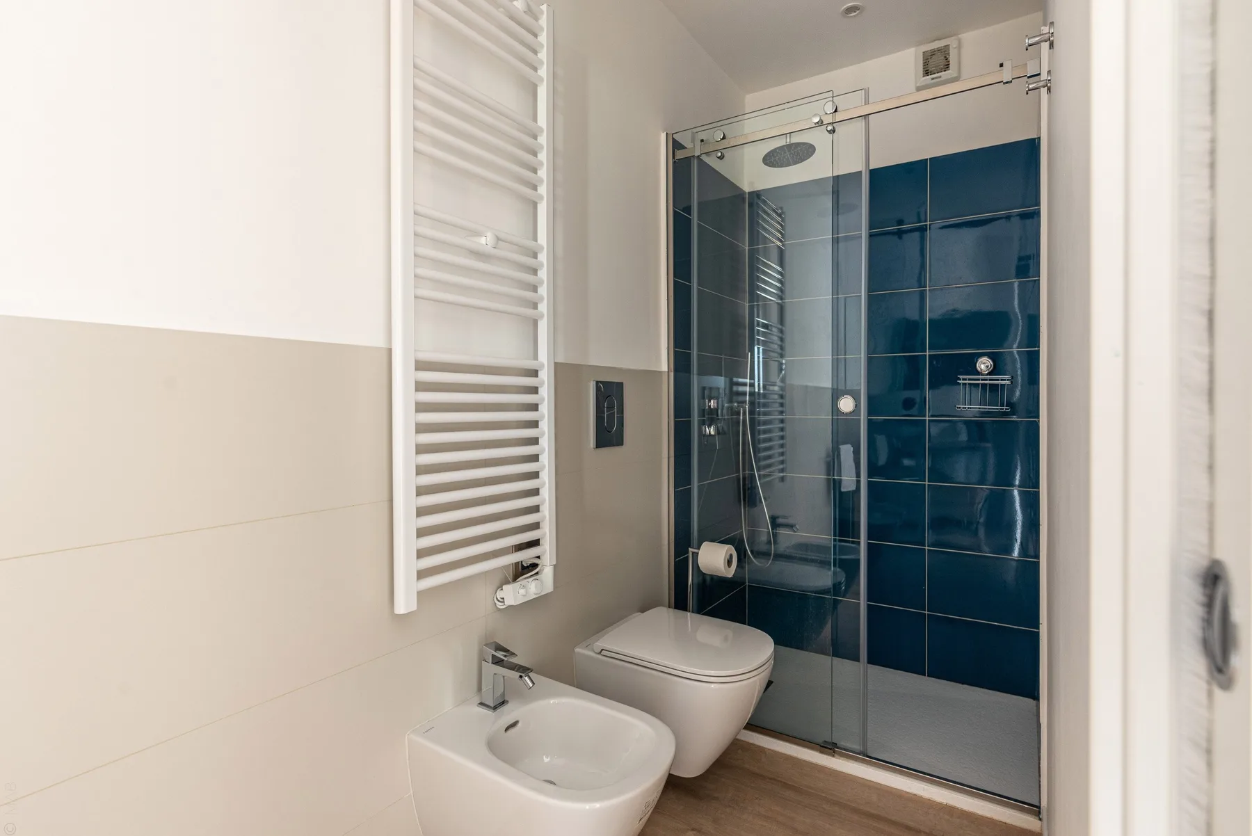 Un baño con una ducha de vidrio y sanitarios blancos.
