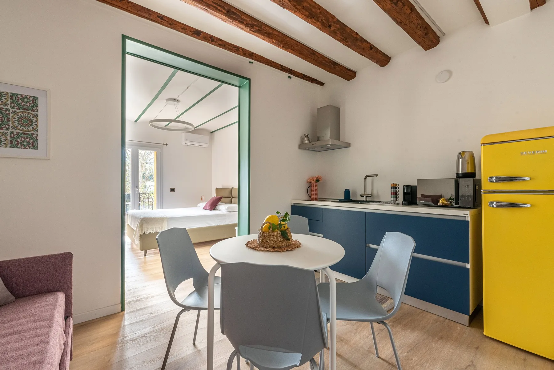 Un comedor con una mesa redonda junto a una cocina azul.