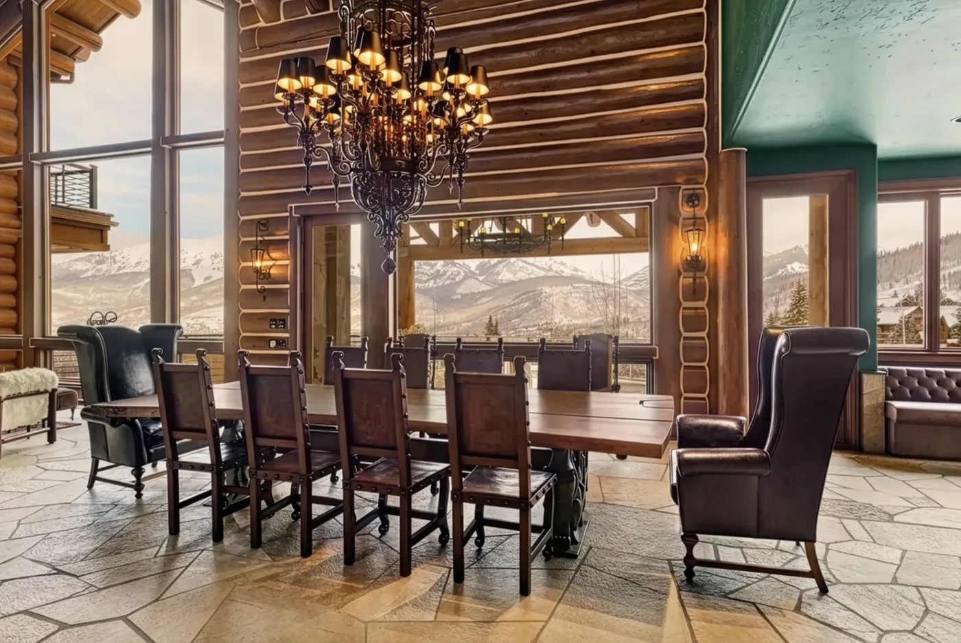 A dining area with a long wooden table and chairs beneath a chandelier.