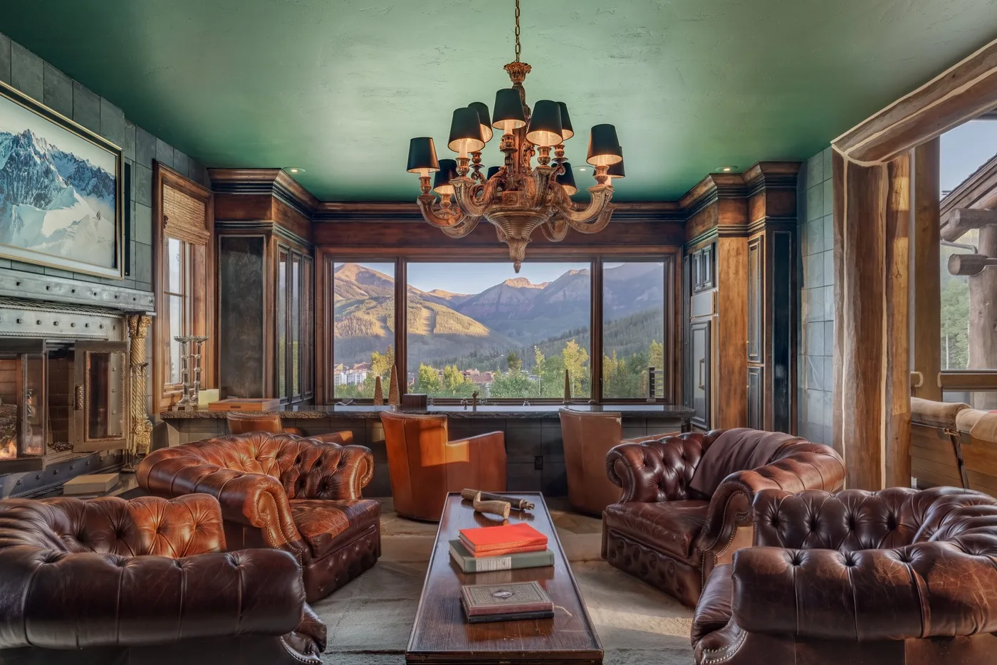 A wood-paneled living room with leather seating and mountain views through large windows.