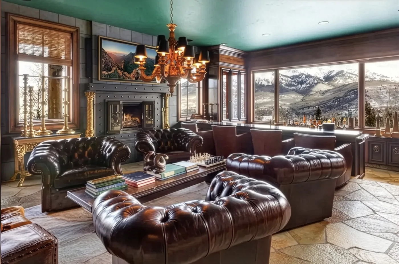A lounge with leather seating and a fireplace overlooks a mountain landscape.