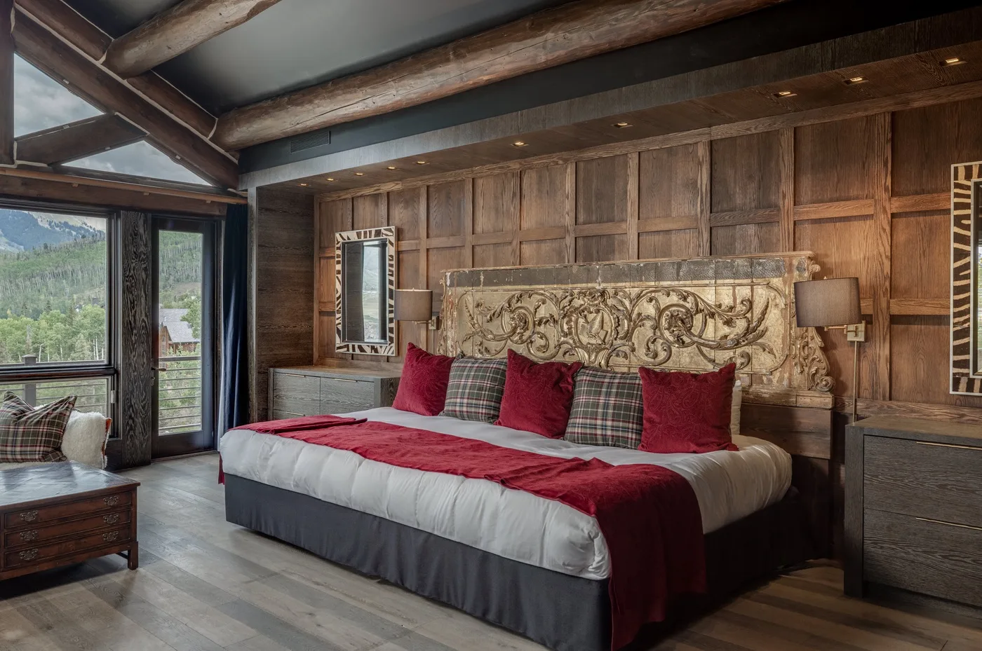A bedroom with a large bed dressed in red and white bedding.