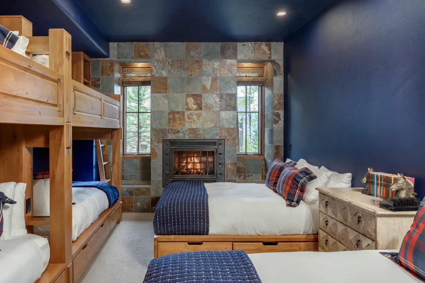 A bedroom with wooden bunk beds, a bed, and a fireplace.