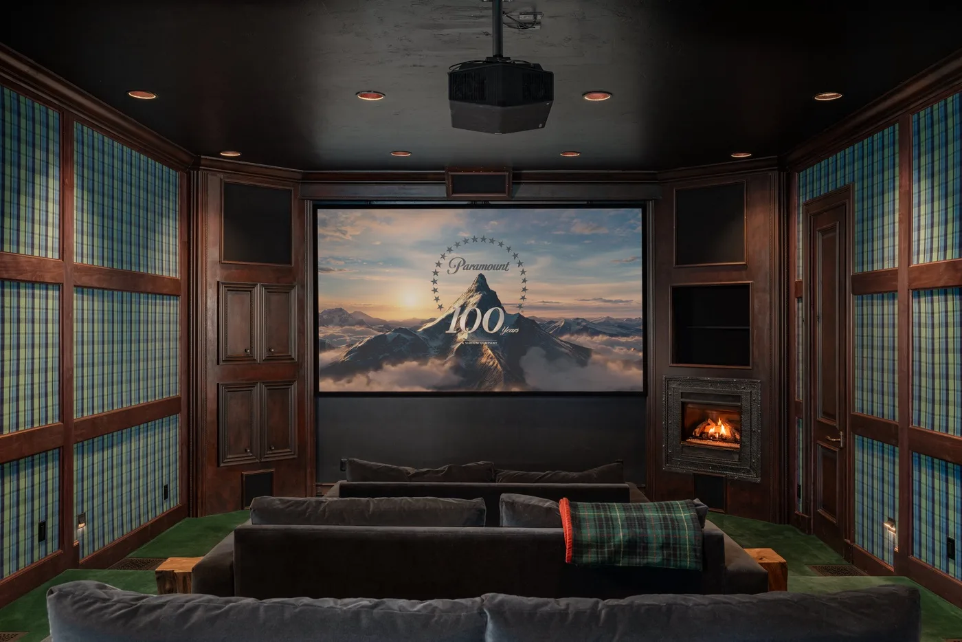 A home theater with rows of seating facing a large screen and fireplace.