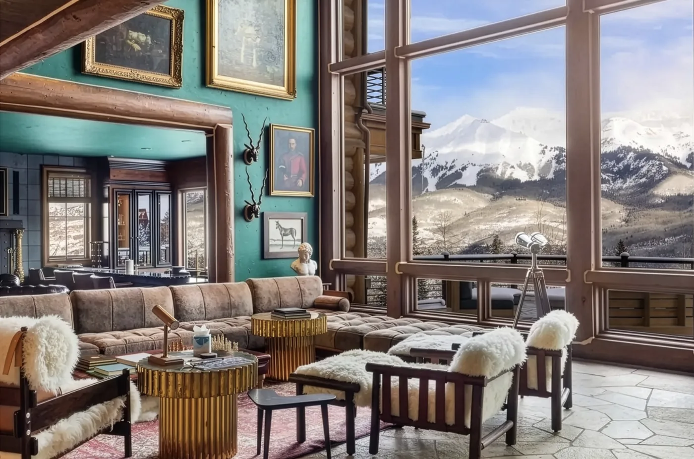 A living room with seating arranged beside large windows overlooking snow-covered mountains.