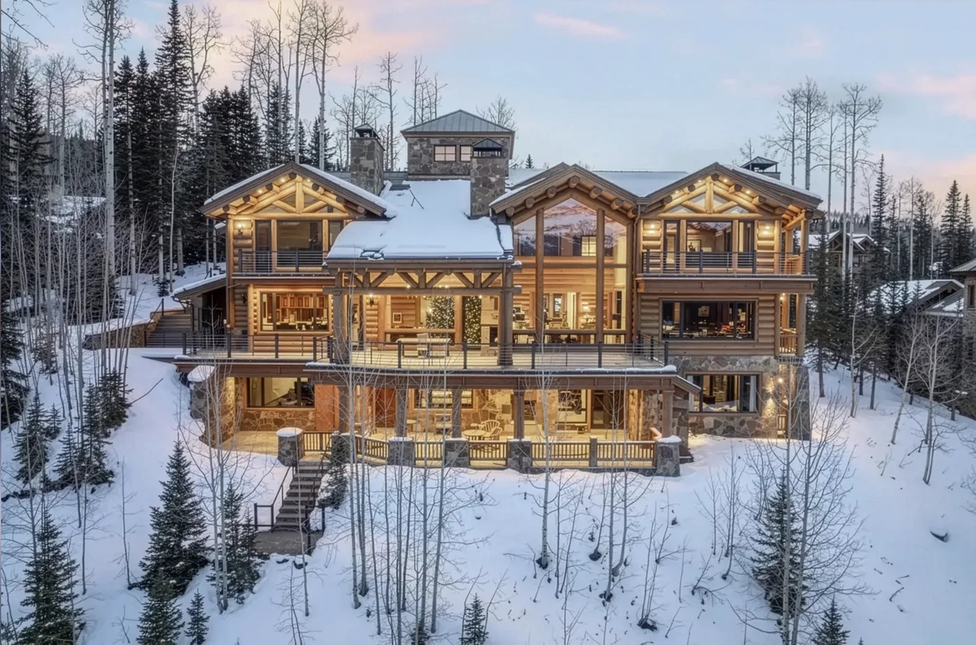 A large timber lodge stands among snow-covered trees.
