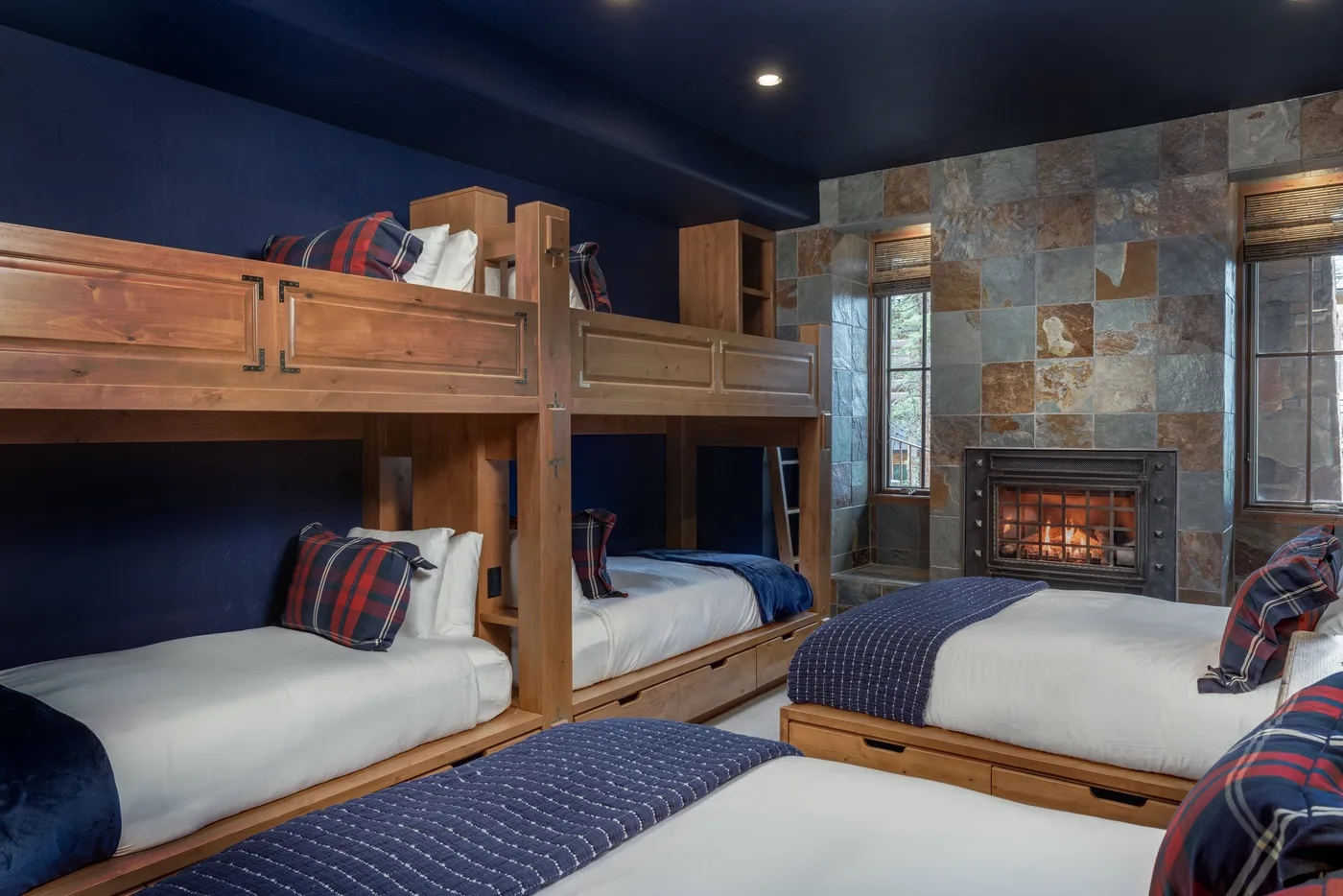 A bedroom with wooden bunk beds, additional beds, and a fireplace.