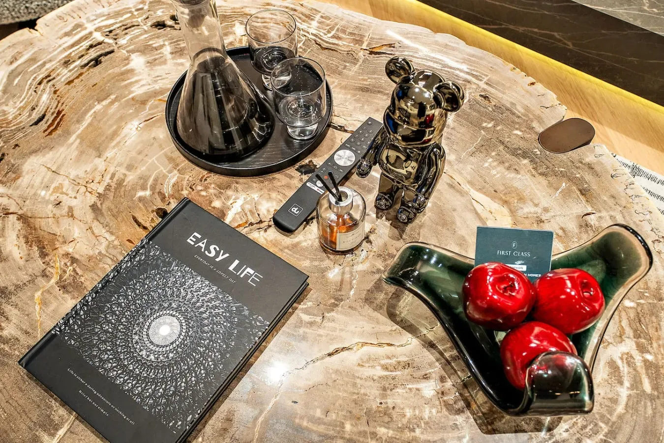 Una mesa de piedra pulida exhibe una bandeja, un libro y objetos decorativos.
