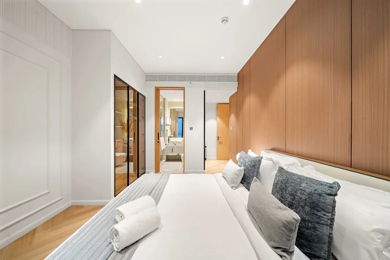 Un dormitorio luminoso con una cama bien hecha y paneles de madera.