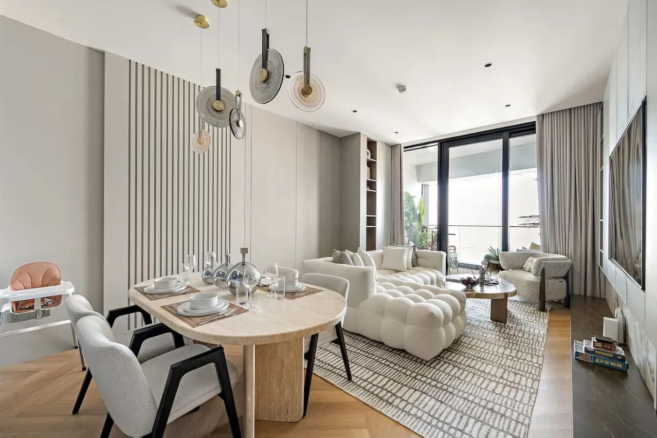 Una luminosa sala de estar y comedor con asientos, una mesa y grandes ventanales.