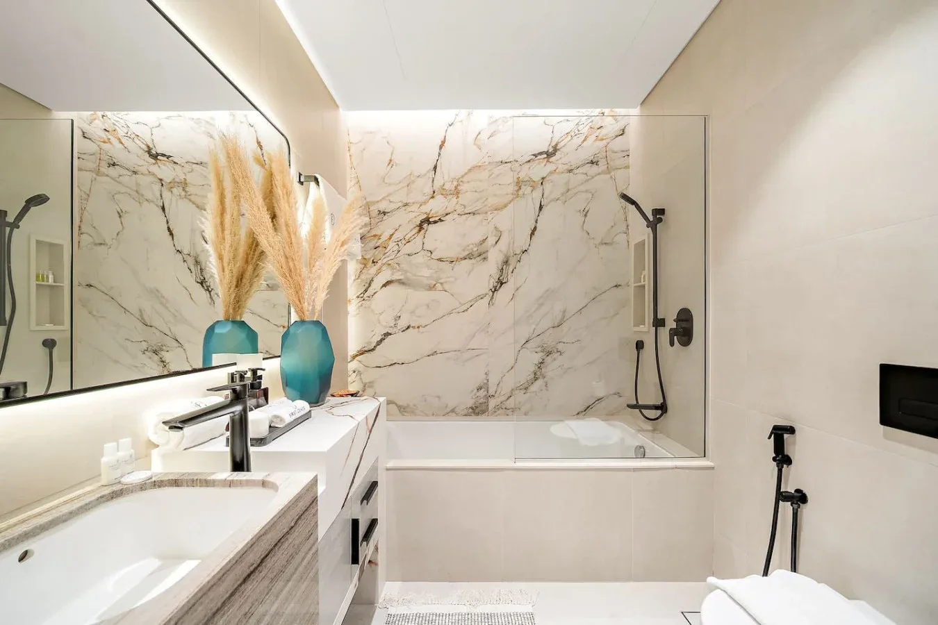 Un baño con bañera, lavabo y grandes paneles veteados en la pared.