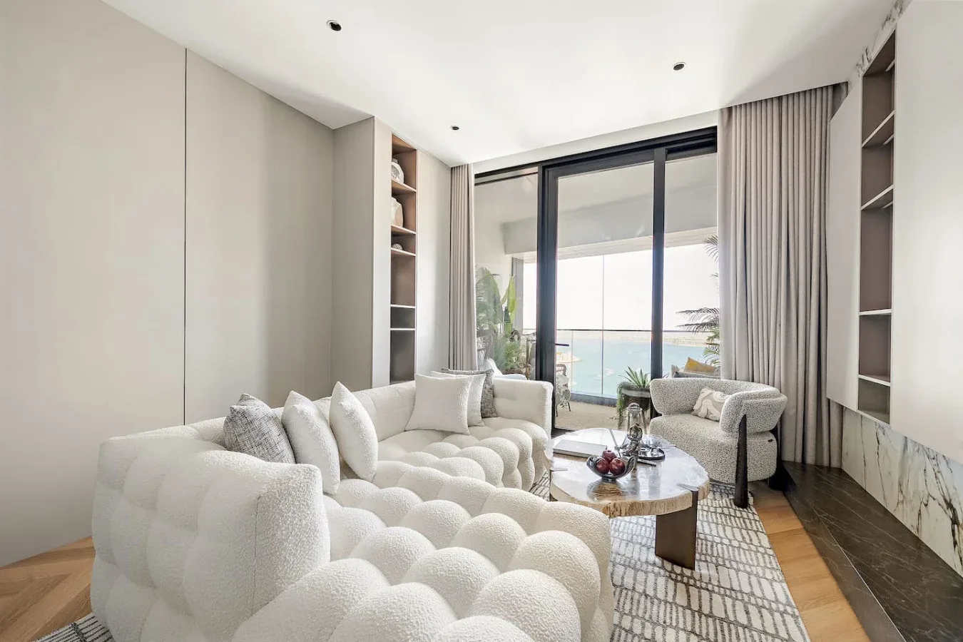 Una sala luminosa con asientos curvos y grandes puertas de vidrio con vista al agua.