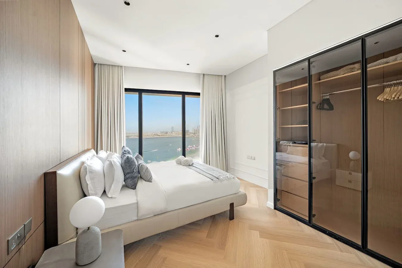 Un dormitorio con una cama junto a ventanales con vistas al agua.