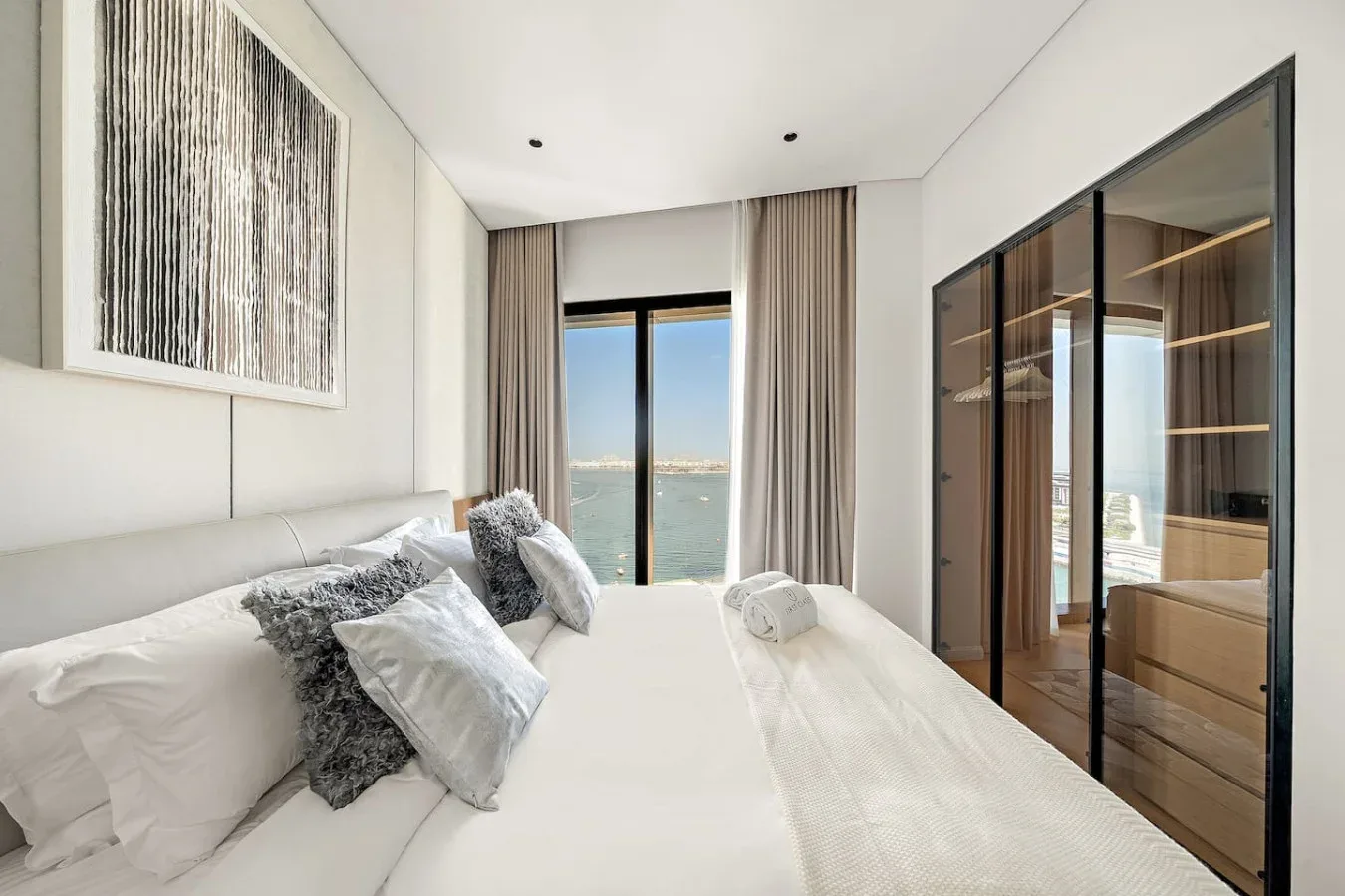 Un dormitorio luminoso con una cama frente a una gran ventana con vista al agua.