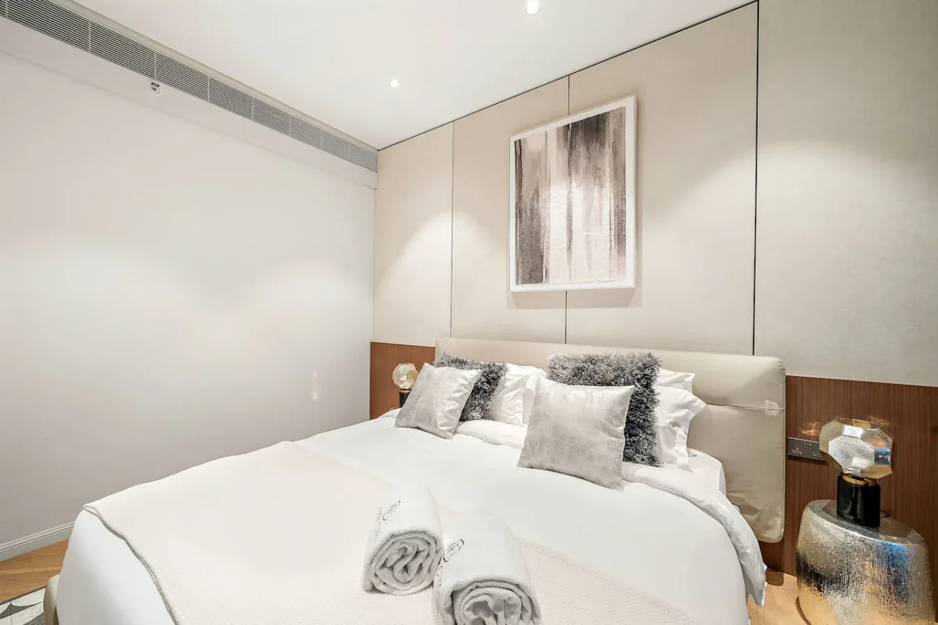 Un dormitorio luminoso con una cama bien tendida y arte enmarcado en la pared.