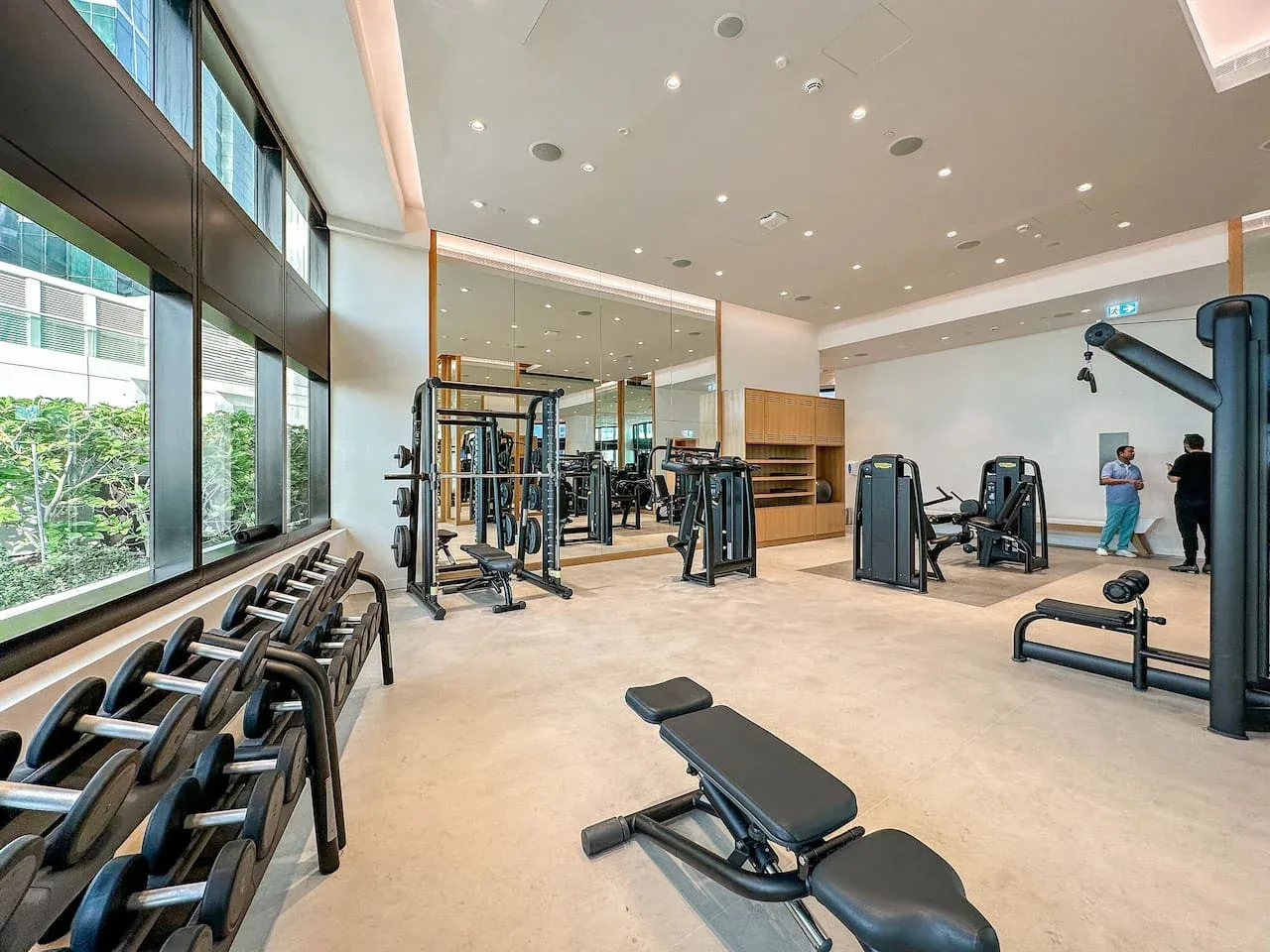 Un gimnasio amplio con máquinas de ejercicio y grandes ventanales.