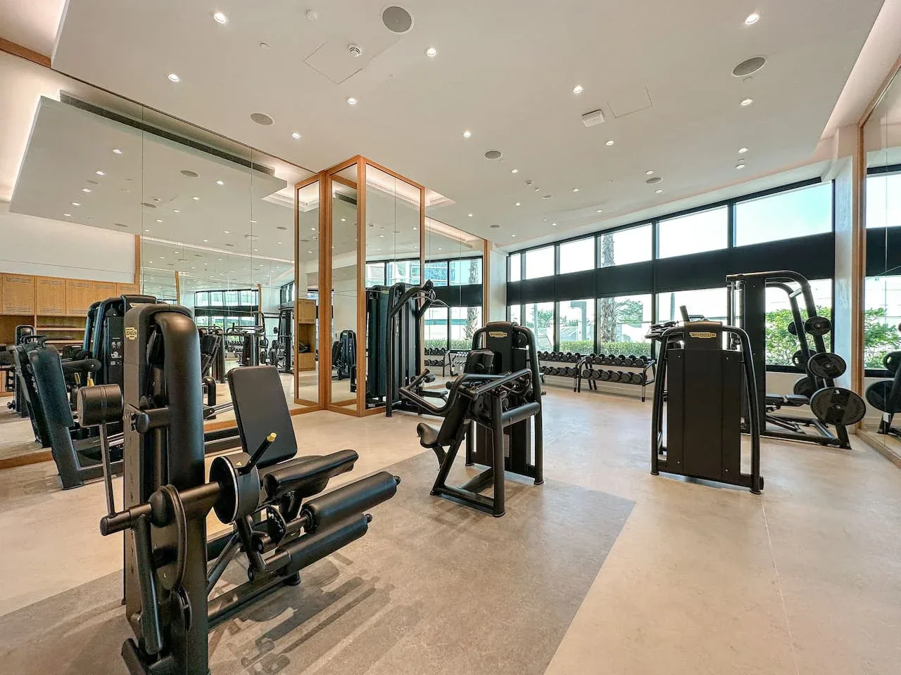 Un gimnasio con máquinas de ejercicio y grandes ventanas.