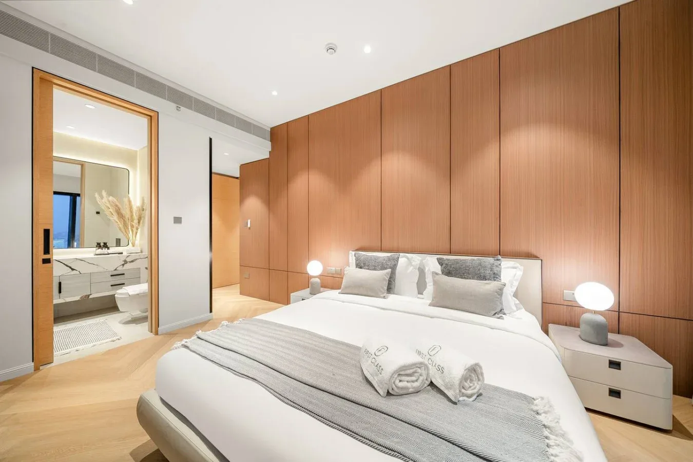 Un dormitorio con una cama bien tendida y paredes revestidas de madera cálida.