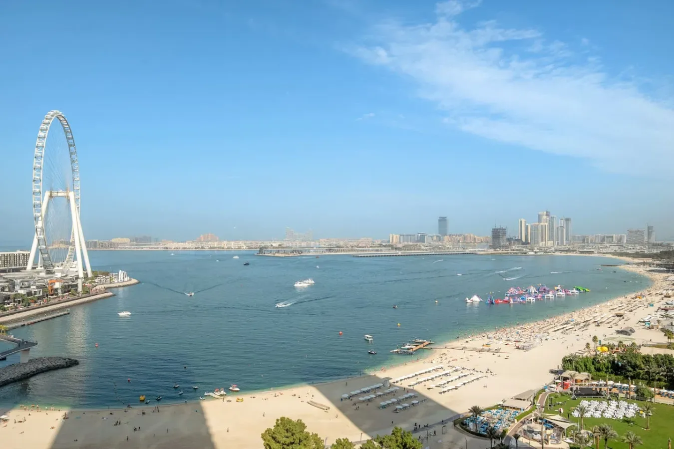 Vista aérea de una playa curva y una bahía, con una gran noria junto a la costa.