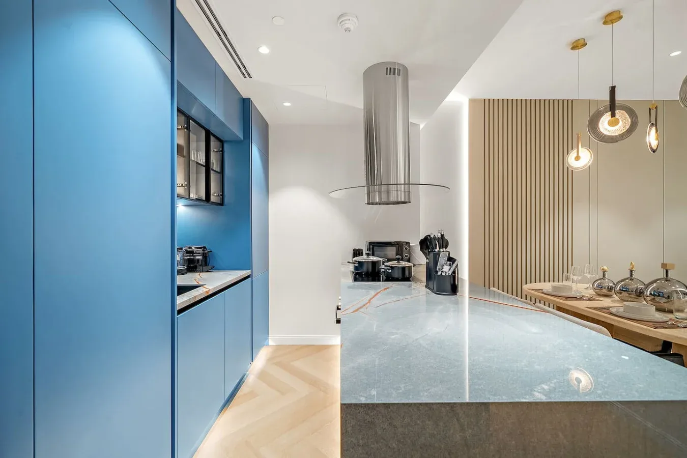 Una cocina moderna con gabinetes azules, una isla central y lámparas colgantes.