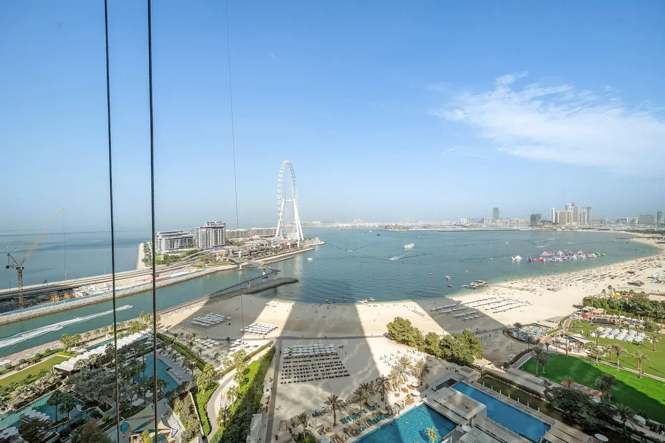Una vista panorámica del paseo marítimo muestra una playa de arena, una marina y una gran noria.