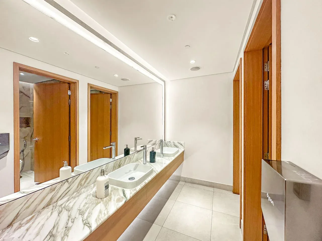 Un baño luminoso con un tocador largo, lavabos y espejos grandes.
