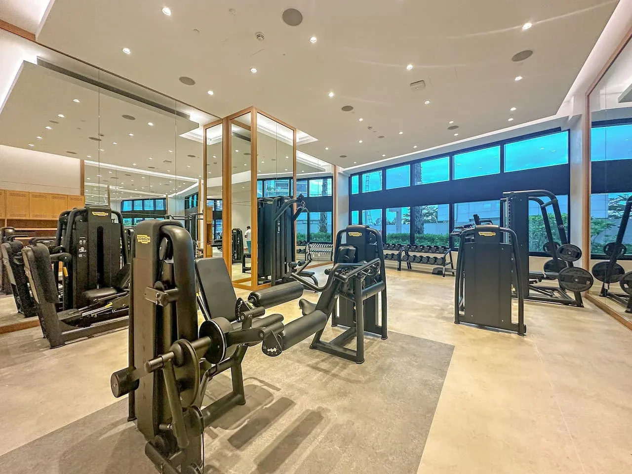 Un gimnasio con máquinas de ejercicio y paredes con espejos.