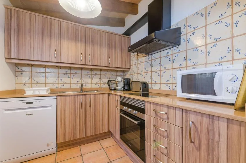 A kitchen with wood cabinetry, a tiled backsplash, and countertop appliances.