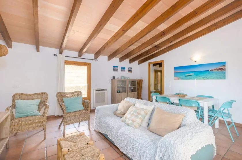 A living room with seating, a dining table, and exposed ceiling beams.