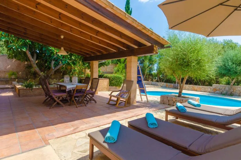 A covered outdoor patio with lounge seating, a dining table, and a pool.