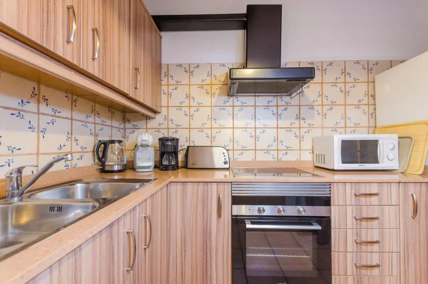A kitchen with wood cabinets, patterned tile walls, and built-in cooking appliances.