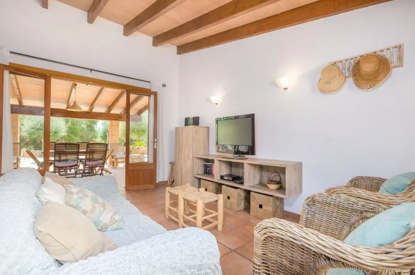 A living room with wicker seating and a television, opening onto a dining area.