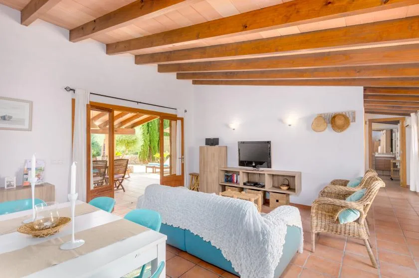 A bright living room with seating, a television, and wide doors opening onto a patio.