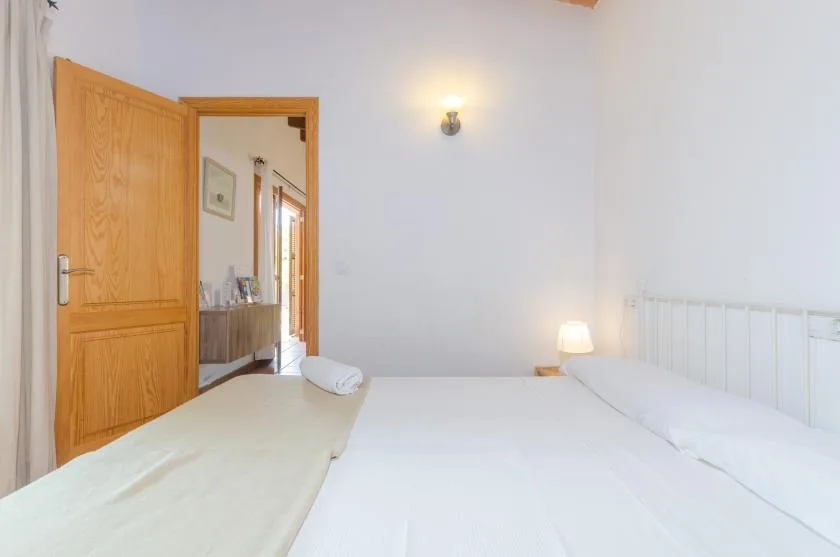 A bedroom with two beds and an open wooden door.