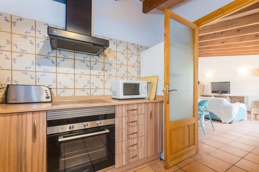A kitchen with a built-in oven and countertop, opening into a bedroom.