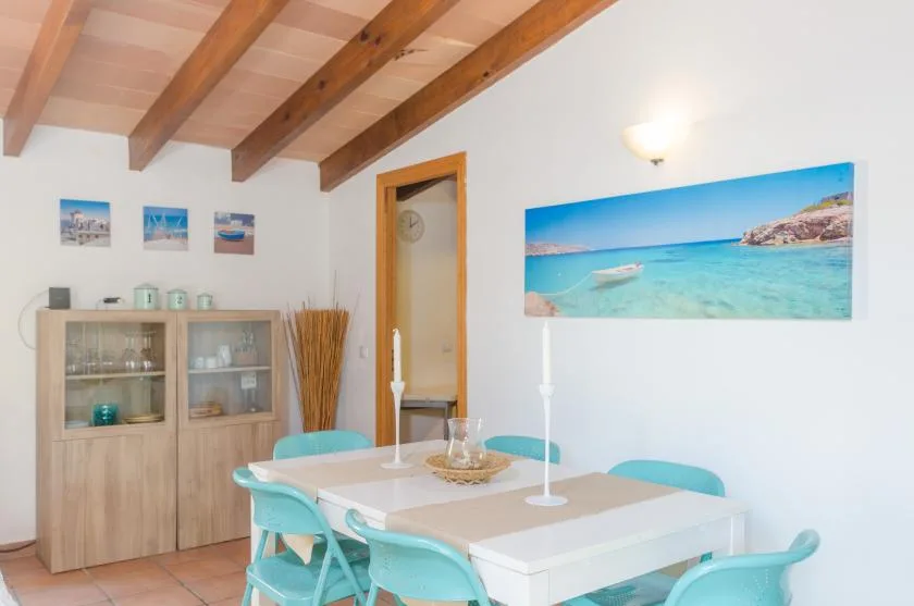 A dining area with a table, turquoise seating, and a coastal wall print.
