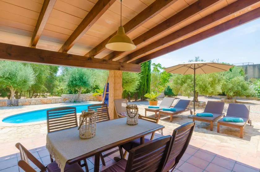 A covered patio dining area overlooks a swimming pool and outdoor seating.