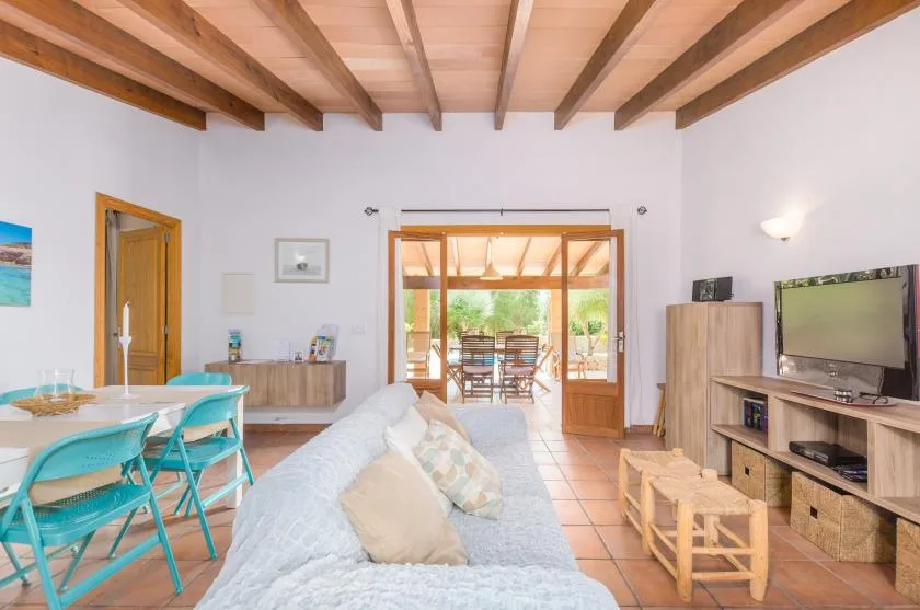 A bright living and dining room opens onto a furnished patio through wide glass doors.