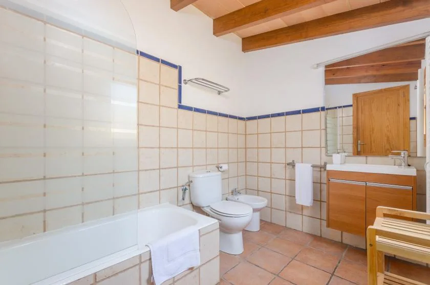 A tiled bathroom with a bathtub, toilet, and wooden vanity.
