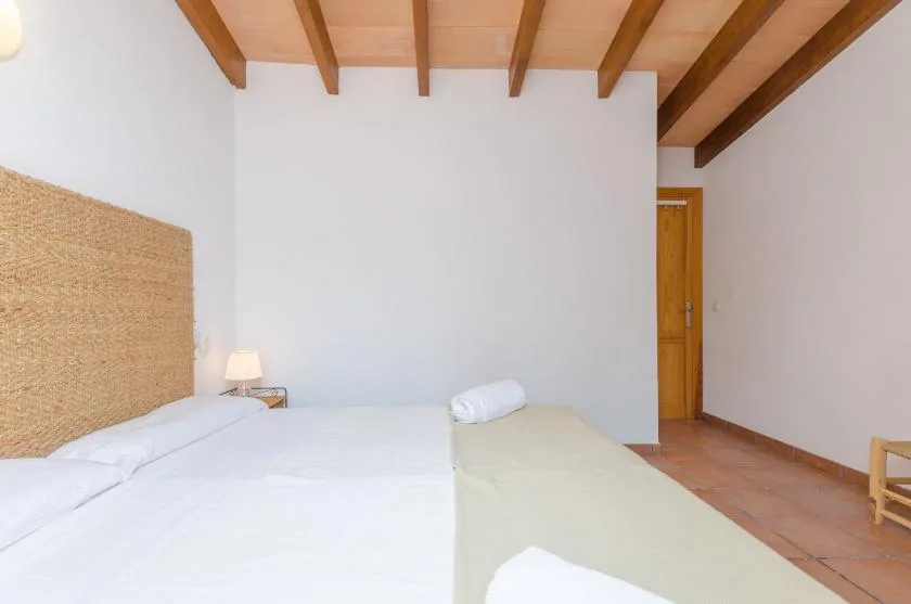 A bedroom with beds beneath exposed wooden ceiling beams.