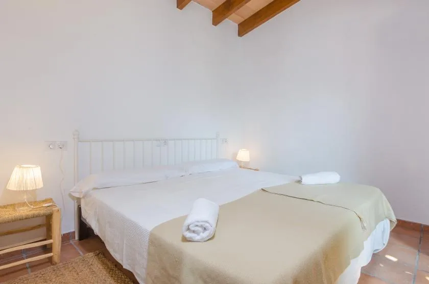 A bedroom with a bed, bedside tables, and exposed wooden ceiling beams.