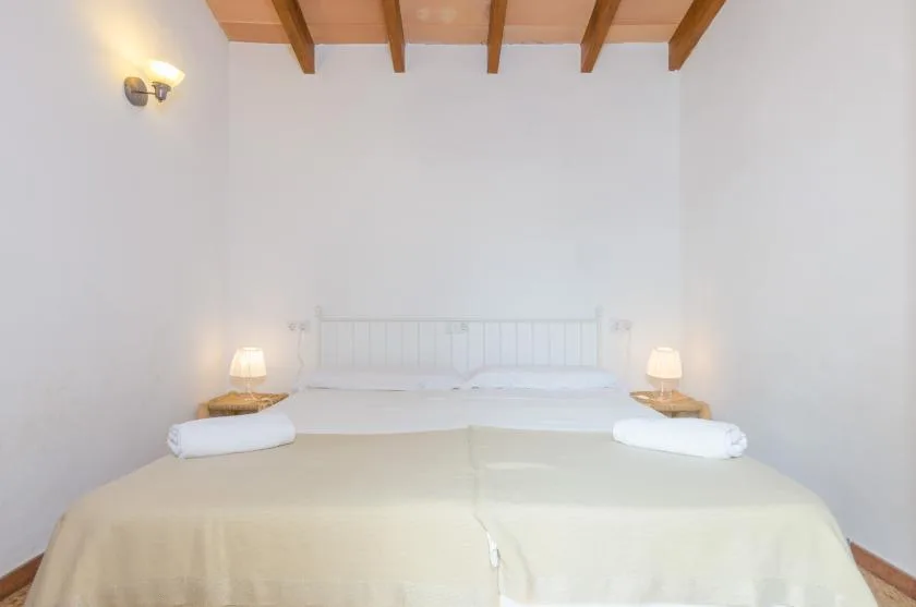 A bedroom with a large bed, bedside tables, and exposed wooden ceiling beams.