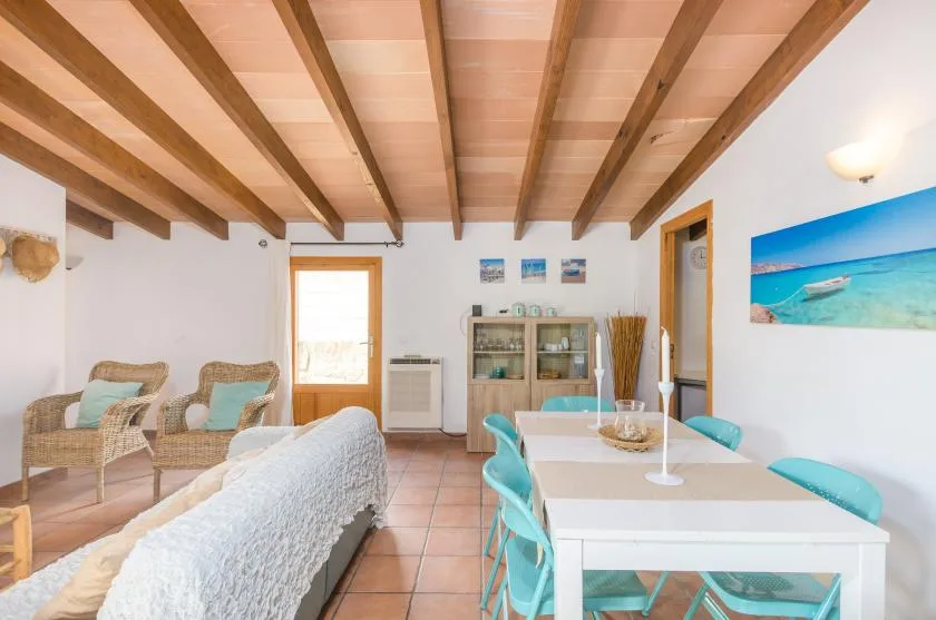 A bright dining and sitting room with a white table and turquoise seating.