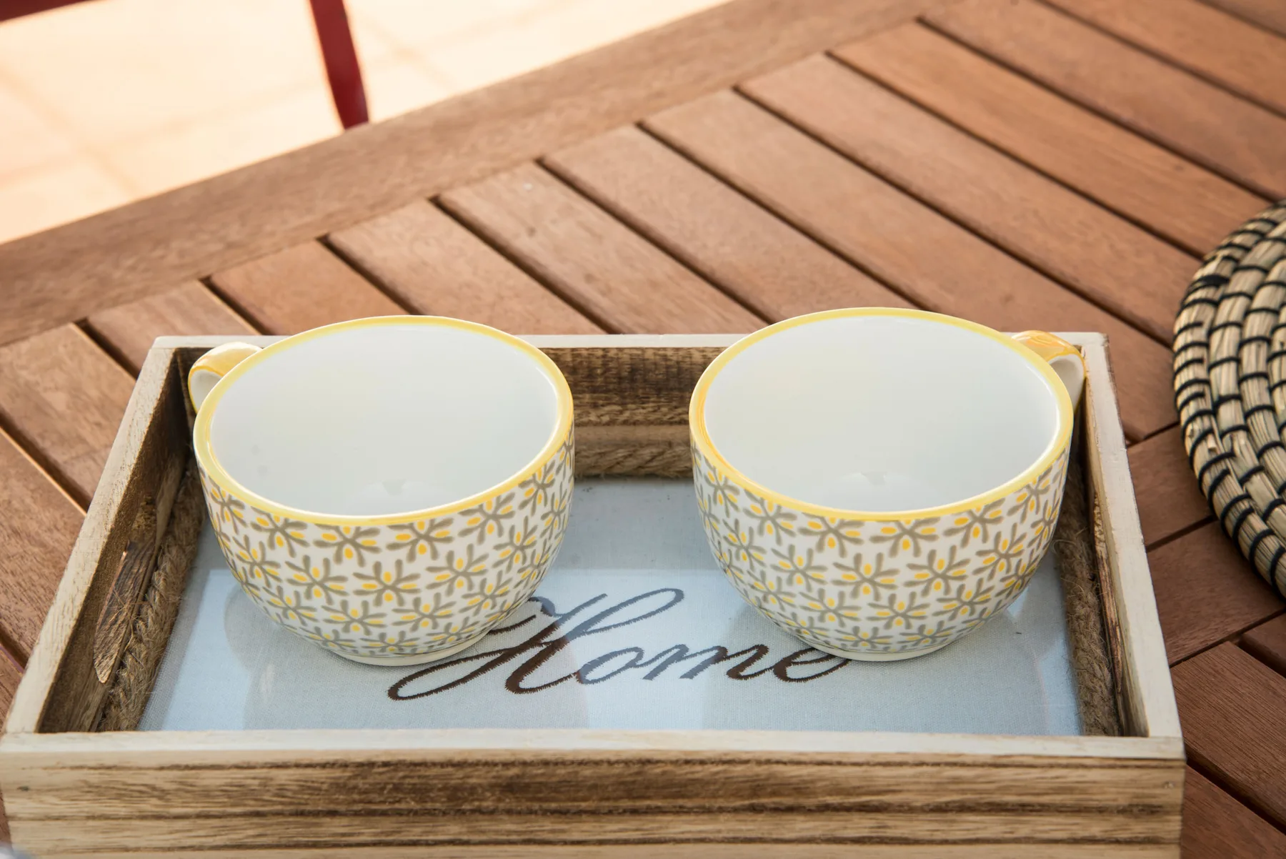 Two patterned bowls sit on a tray atop a wooden table.